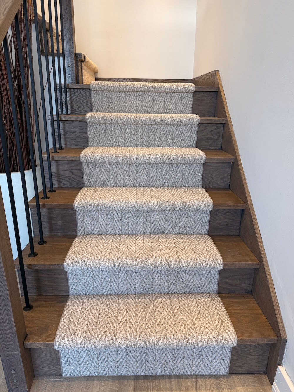 Staircase with wooden steps and patterned gray carpet runner
