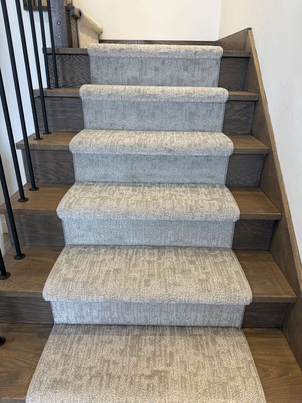 Gray stair runner on dark wood staircase with black spindles