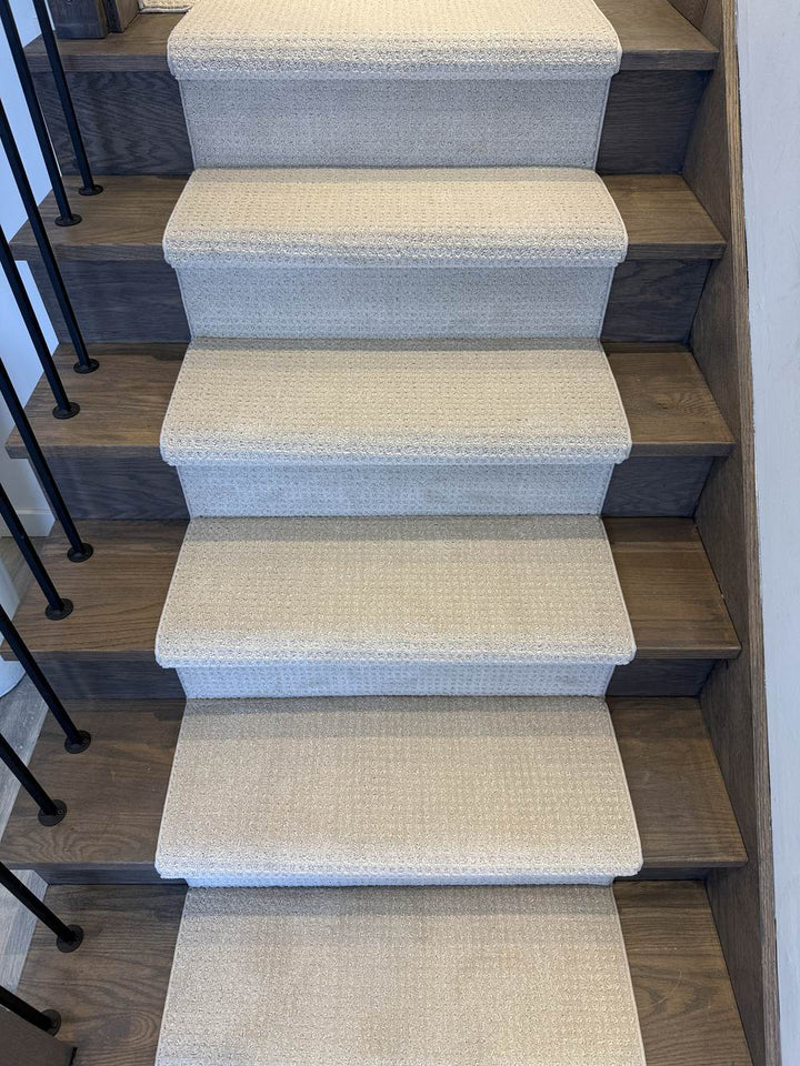 Light greige stair runner on dark wood staircase with black spindles
