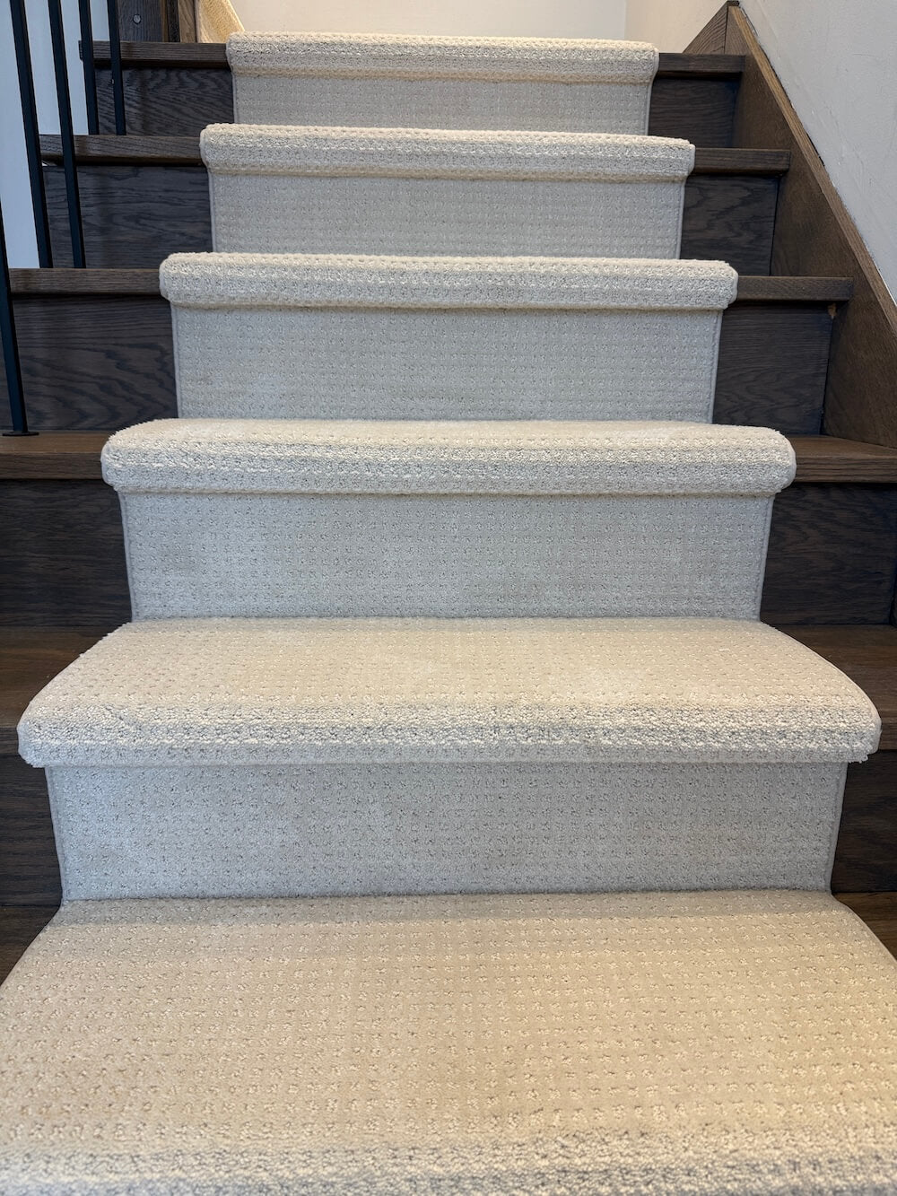 Light beige stair runner on dark walnut stairs