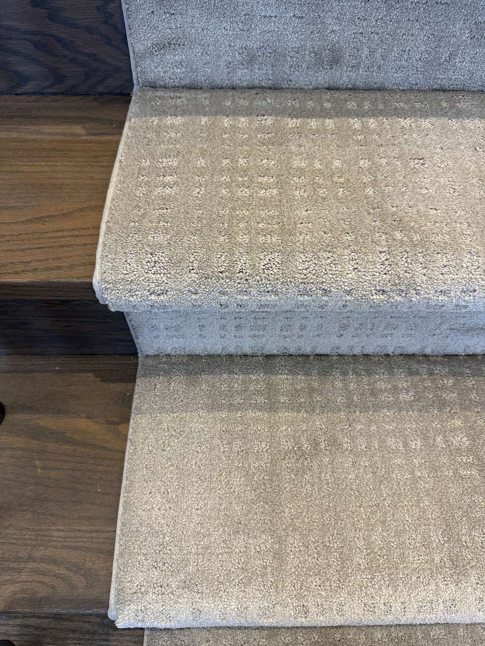 Close-up of Tanager Lodge Brown Bag stair runner carpet on dark stained stairs