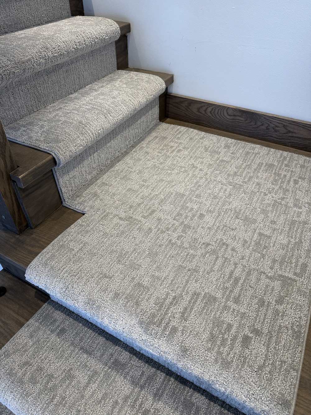 Stair runner with matching landing carpet on dark hardwood stairs
