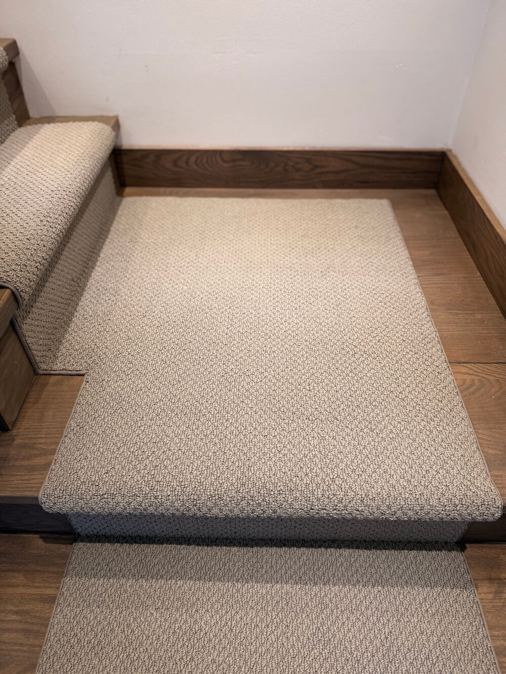 Gray textured stair runner on wooden stairs with a white wall background