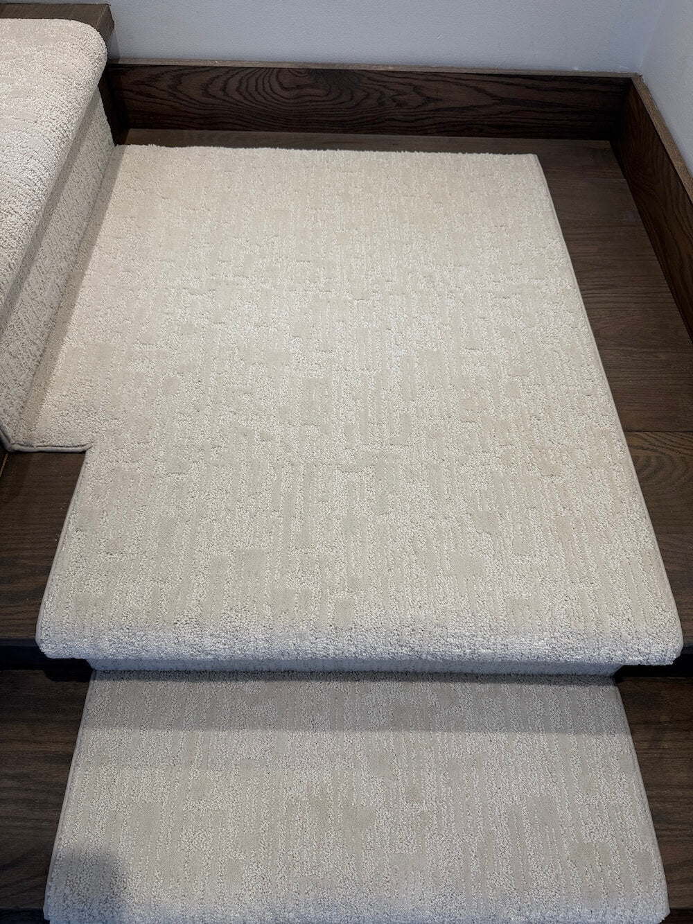 Three light beige textured carpet runner strips arranged on dark wood stairs.