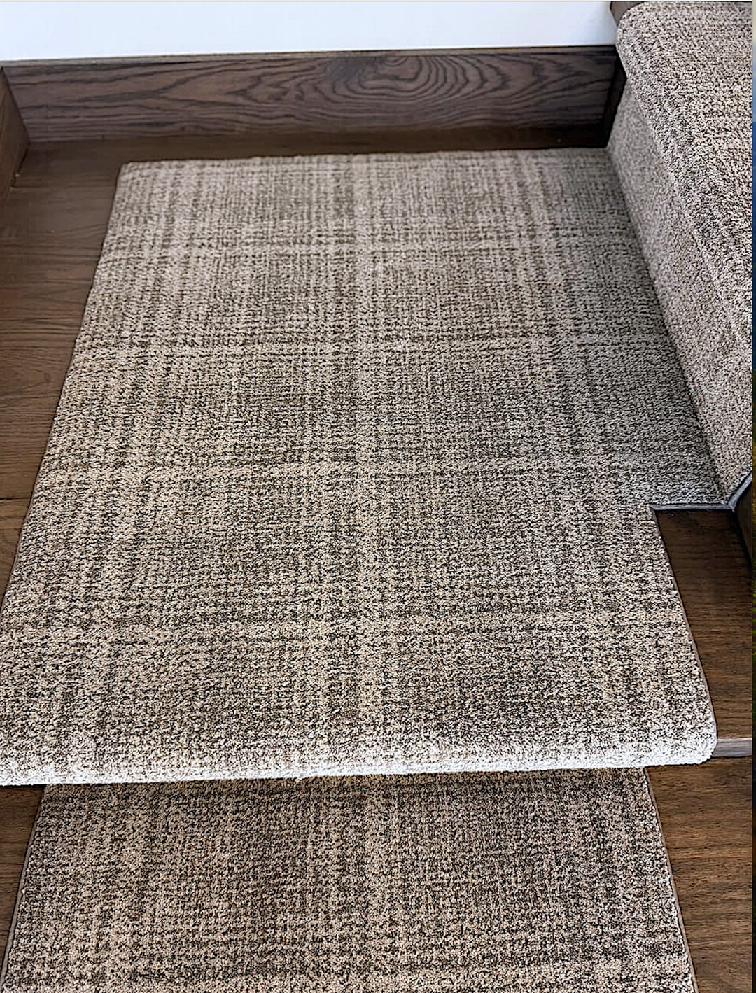 Textured stair runner on a wooden stairs next to a sofa.