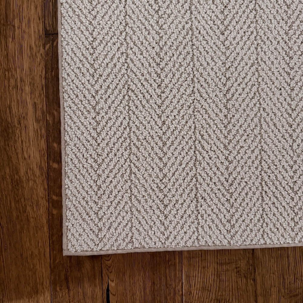 Textured rug with a herringbone pattern on a wooden floor