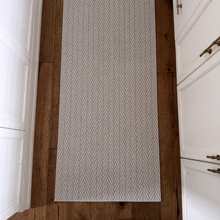 Patterned rug on a wooden floor with white walls and cabinets.