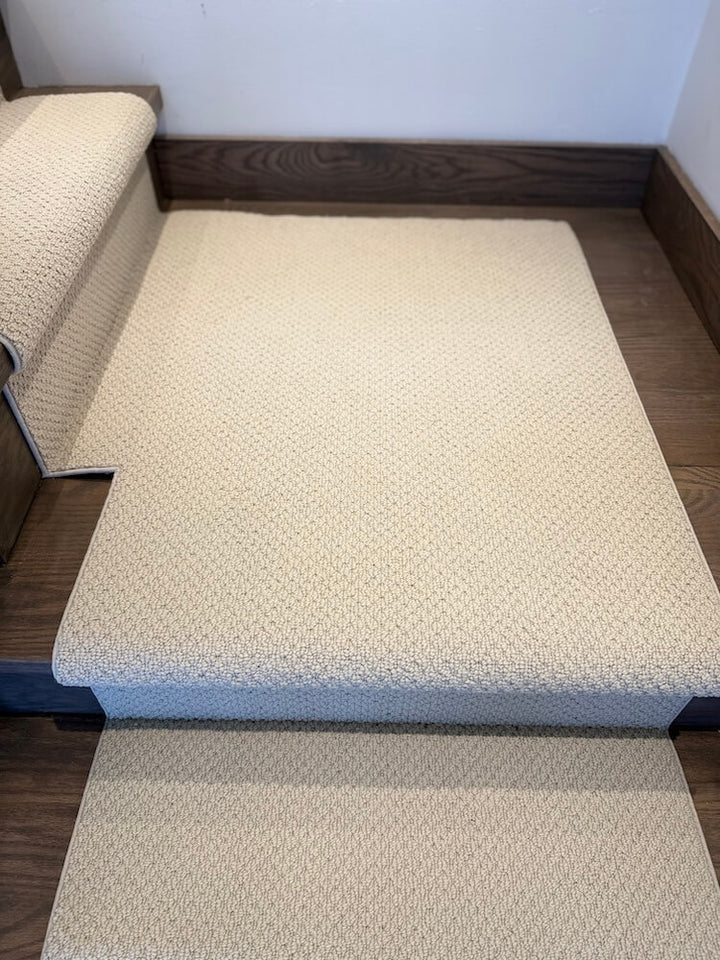 Beige textured stair runner on wooden stairs with a white wall background