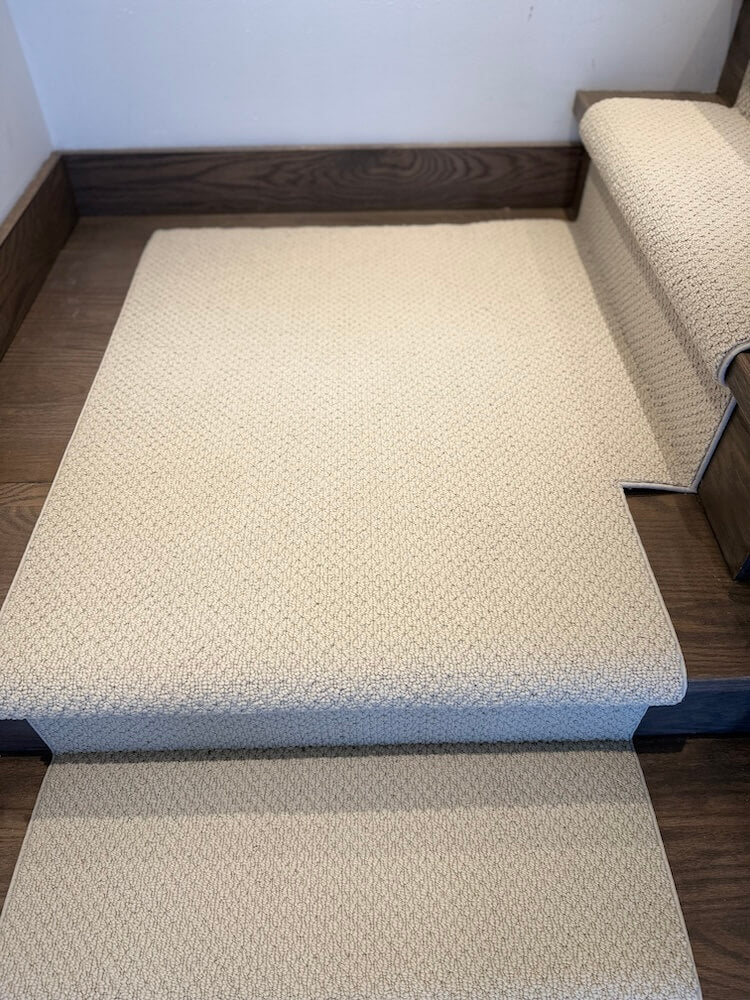 Beige textured stair runner carpet rug on a wooden staircase.