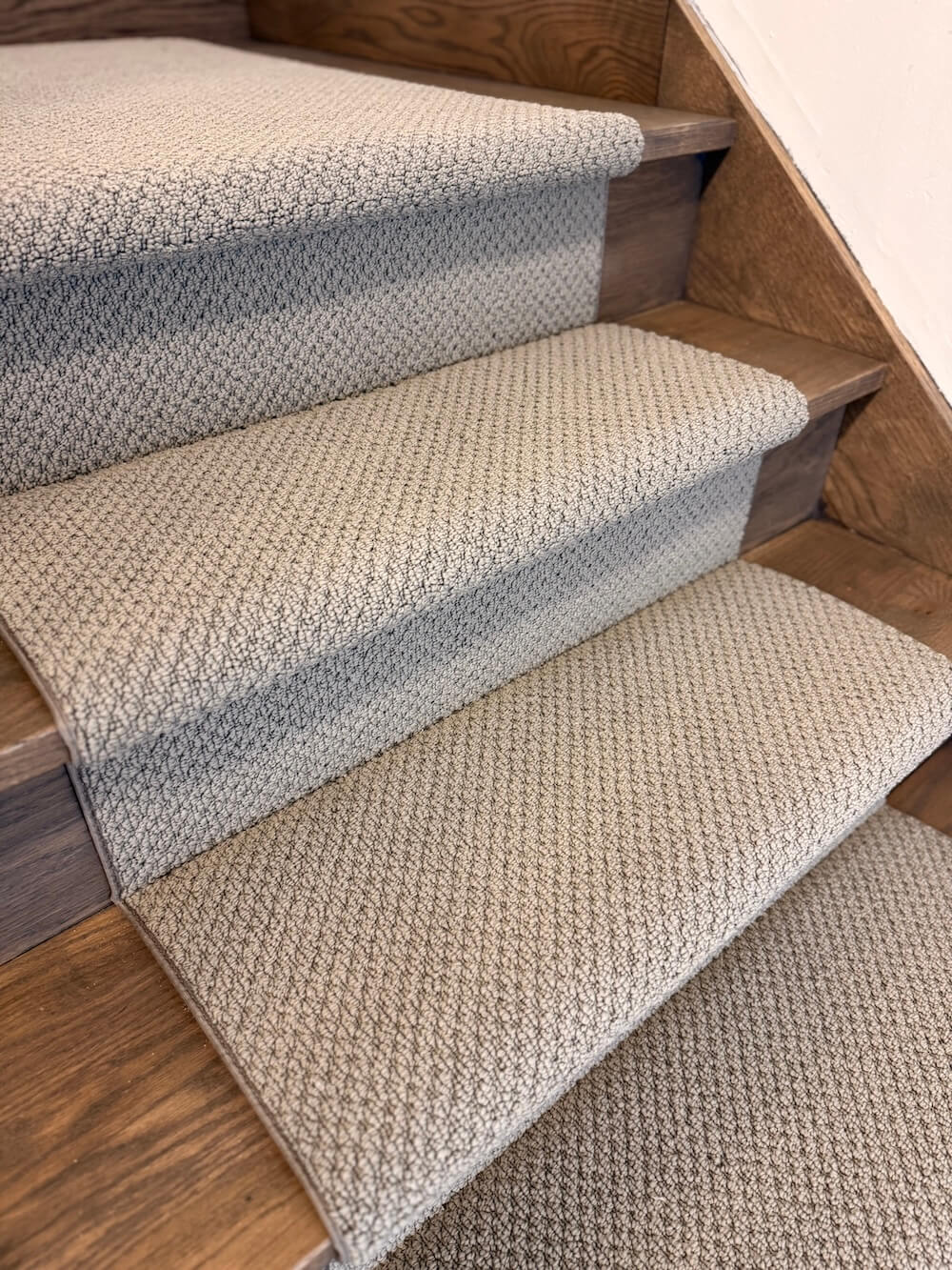 Staircase with textured gray carpet on wooden steps