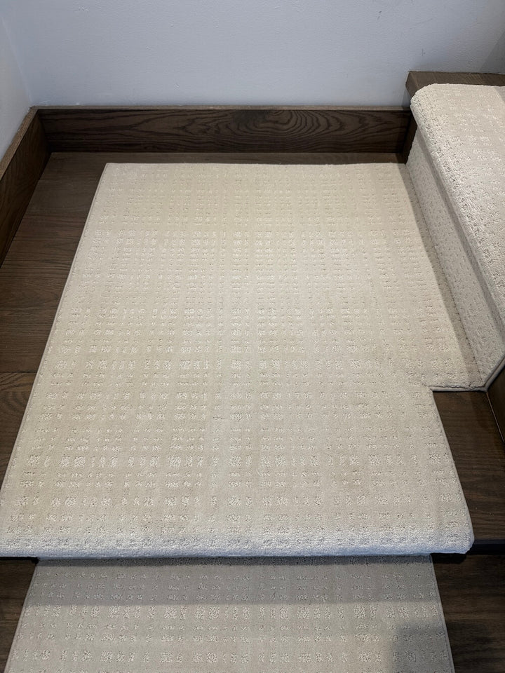 A light beige textured stair carpet pad shown installed on a wooden staircase, with a matching stair rail visible on the right side.