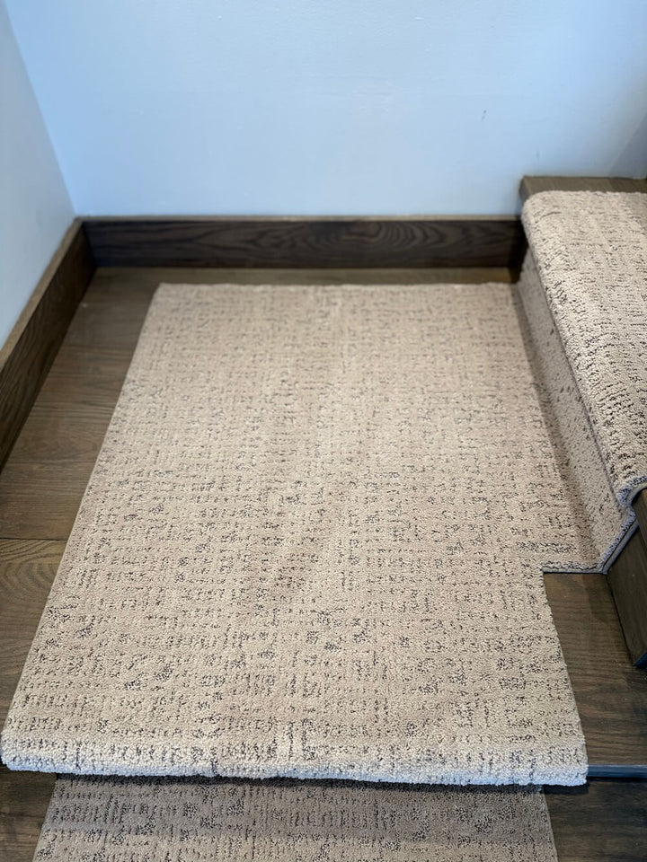 Beige textured stair runner rug on a wooden floor with a white wall background