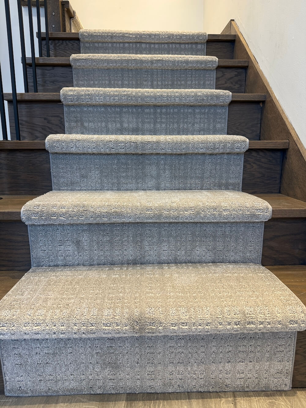 Staircase with gray stair runner on dark wood stairs with white walls
